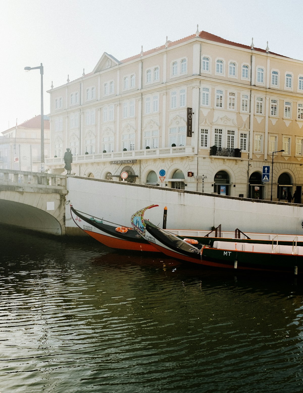 Colourful moliceiro boats moored on Aveiro canal with the Aveiro Palace Hotel in the background
